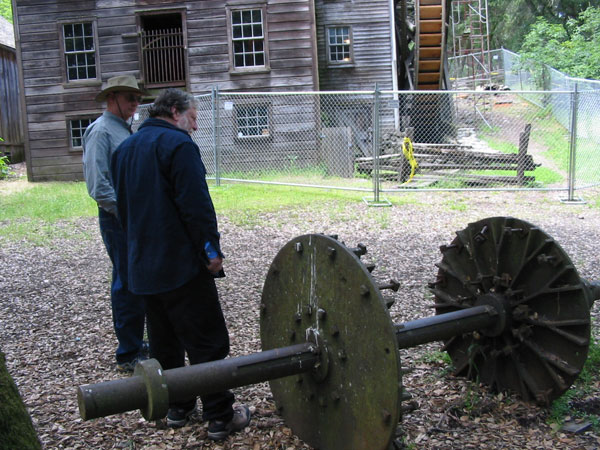 Dennis Mueller and John de Marchi look at water wheel axle